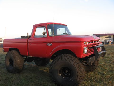 1974 Ford F-100 - This red Ford pickup truck is modified with large off-road tires and a lifted suspension.