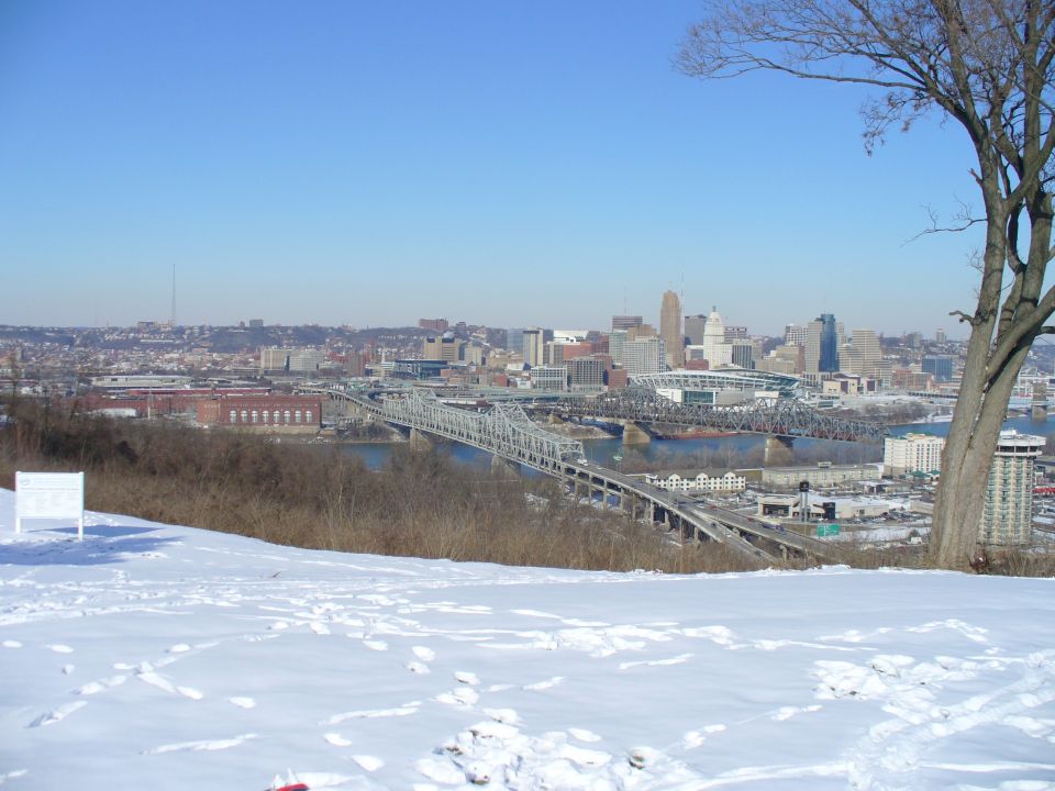 Snowy foreground with a distant city skyline and bridges over a river