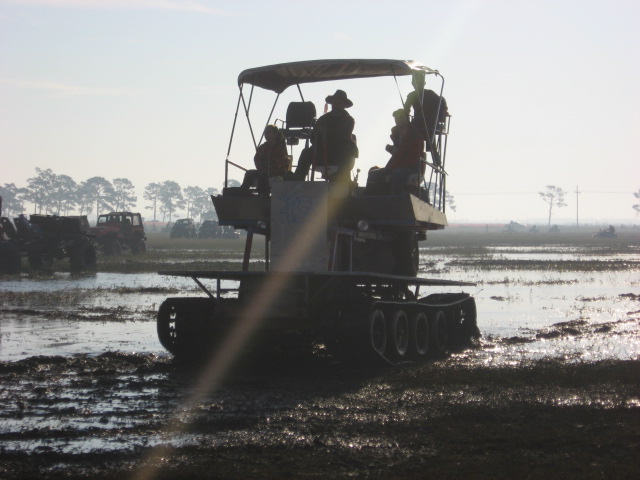 Tracked amphibious vehicle with people in a muddy field
