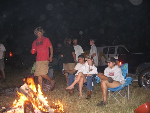 1974 Ford F-100 - A group of people enjoy a campfire at night, with a white van visible in the background.