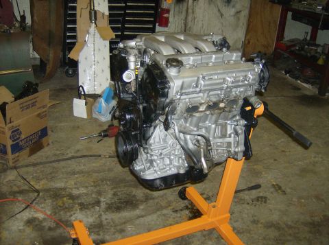 1996 Ford Probe - Engine on a stand in a workshop, with tools and boxes nearby.