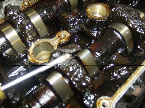 1996 Ford Probe - The engine's internal components are heavily coated in dark, viscous sludge, indicating a severe lack of maintenance.