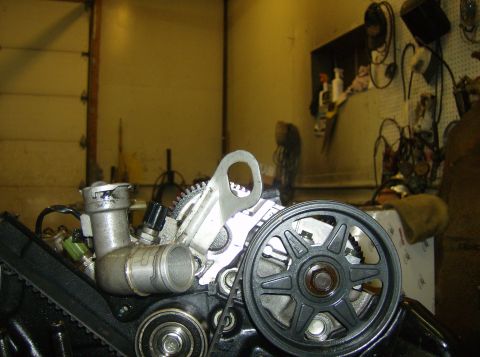 1996 Ford Probe - Close-up view of an engine's pulley system and water outlet assembly, likely in a workshop setting.