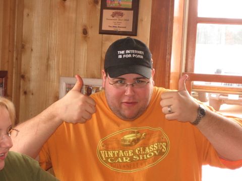 1996 Ford Bronco - A man gives two thumbs up while wearing a t-shirt with a vintage car show graphic and a cap with a humorous slogan.