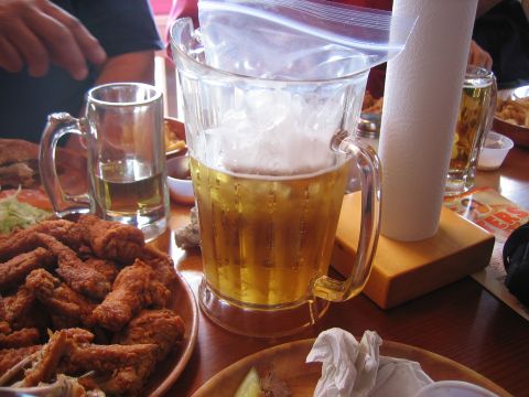 1996 Ford Bronco - A table setting with a large pitcher of beer, a plate of fried chicken wings, and a mug of beer.