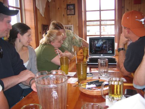1996 Ford Bronco - A group of friends gathers around a table, engrossed in a video playing on a laptop.