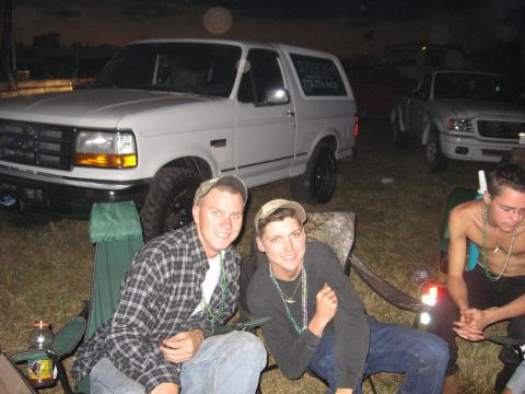 1974 Ford F-100 - Two men sit in camping chairs in front of a white Ford Bronco and a white Ford Ranger at dusk.