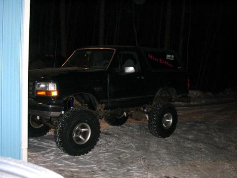 1995 Ford Bronco - A black lifted Ford Bronco with "Miss Kitten" written on the side is parked outside at night.
