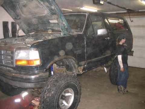 1995 Ford Bronco - A 1995 Ford Bronco is shown with its hood open, undergoing work in a garage.
