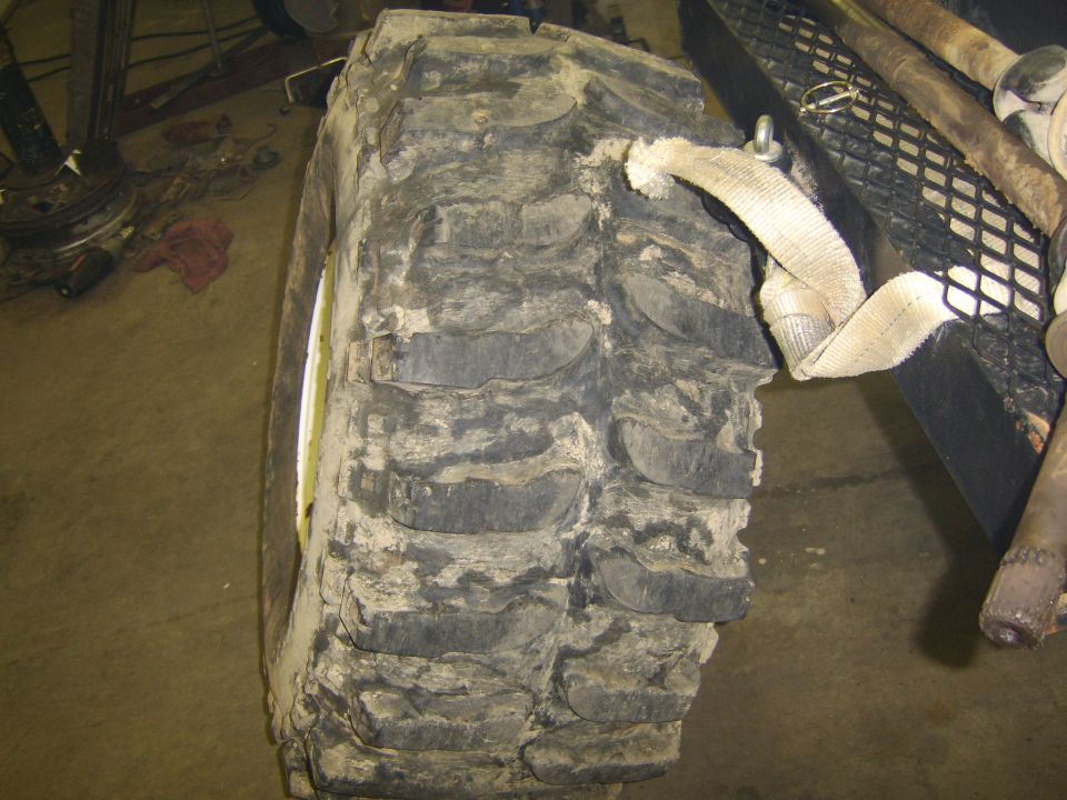 Close-up of a large, muddy off-road tire with aggressive tread