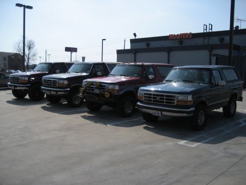 1986 Ford Bronco - A lineup of Ford trucks and a Bronco are parked outside a Hooters restaurant.