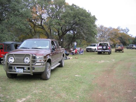 1996 Ford Bronco - A maroon Ford F-250 Super Duty pickup truck is parked in a grassy area with other vehicles and people enjoying an outdoor gathering.
