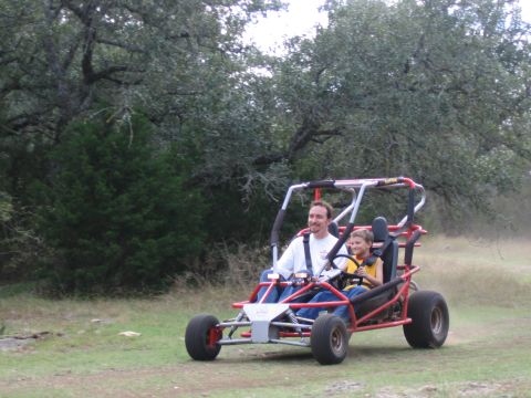 1996 Ford Bronco - Two people enjoy a ride in a go-kart through a wooded area.