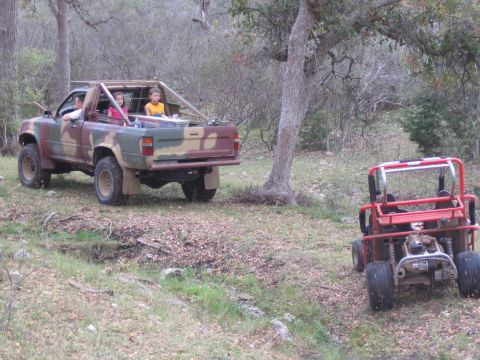 1996 Ford Bronco - Two vehicles, a pickup truck and an off-road buggy, are parked in a natural, wooded setting.