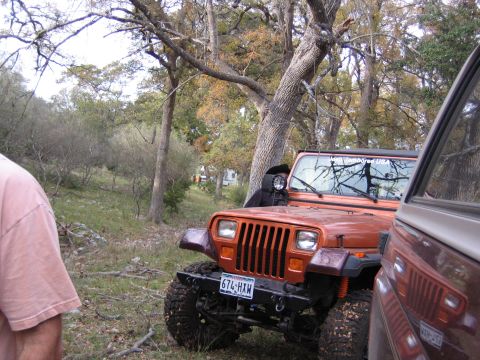 1996 Ford Bronco - A Jeep Wrangler is parked in a wooded area next to another vehicle.