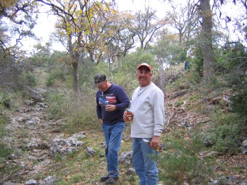 1996 Ford Bronco - Two men are standing in a wooded area with rocky terrain and trees.