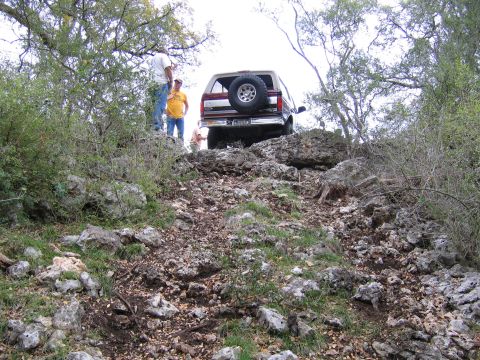 1996 Ford Bronco - A 1996 Ford Bronco navigates a steep, rocky trail with onlookers observing its progress.