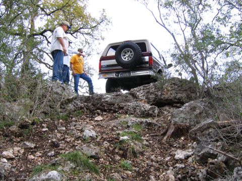 1996 Ford Bronco - A 1996 Ford Bronco navigates a steep, rocky incline with people watching.