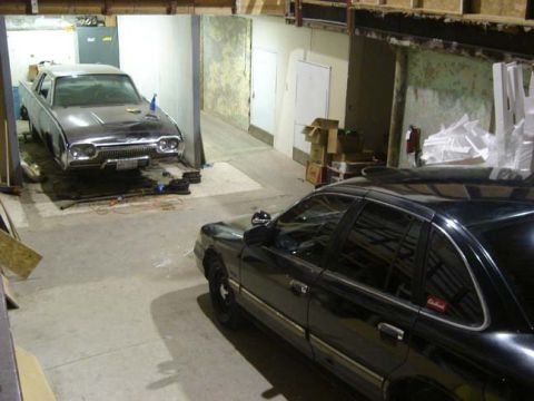 1992 Ford Crown Victoria - Two sedans are parked in a garage, one on a lift and the other in the foreground.