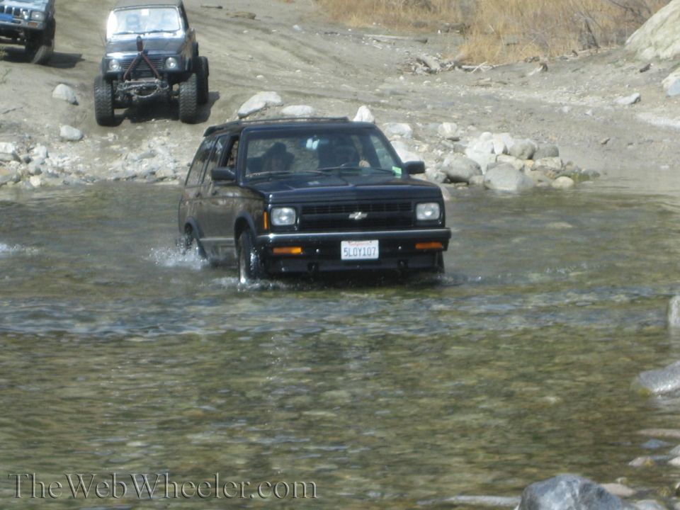 Black 1987 Chevrolet S-10 Blazer driving through shallow water, front view. License plate 5L0Y107