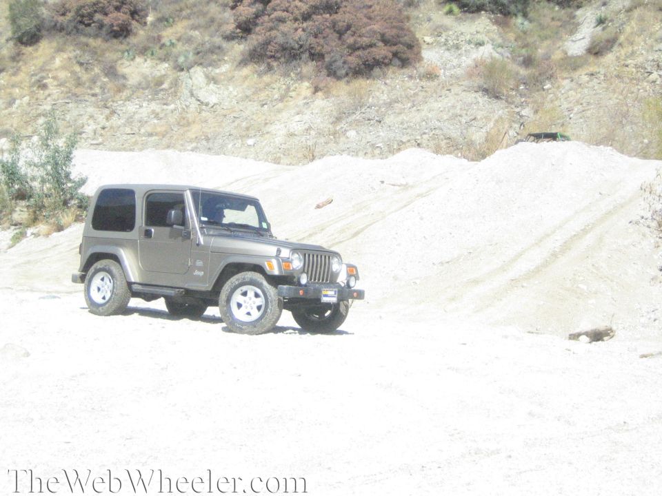 Tan Jeep Wrangler parked on a dirt hill