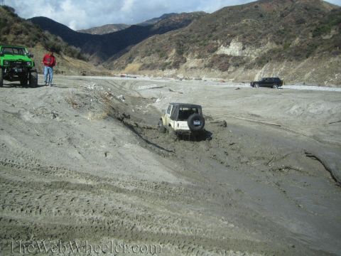 1987 Suzuki Samurai - Multiple off-road vehicles navigate a muddy terrain in a mountainous area.