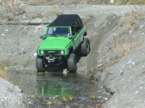 1987 Suzuki Samurai - A green 1987 Suzuki Samurai navigates a rocky stream bed on an off-road trail.