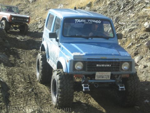 1987 Suzuki Samurai - A blue 1987 Suzuki Samurai navigates a challenging off-road trail, with another vehicle following closely.