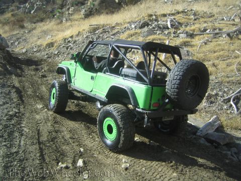 1987 Suzuki Samurai - A modified green off-road vehicle navigates a dirt trail on a hillside.