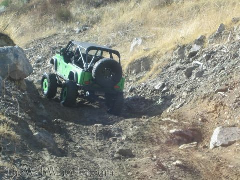 1987 Suzuki Samurai - Off-road Jeep Wrangler navigates a steep, rocky incline on a sunny day.