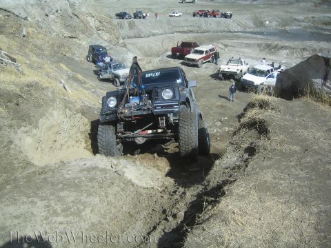 1987 Suzuki Samurai - A modified 1987 Suzuki Samurai navigates a muddy off-road course with other vehicles in the background.