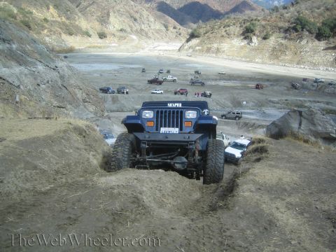 1987 Suzuki Samurai - Multiple off-road vehicles gathered in a dry, hilly terrain, with one Jeep Wrangler leading the pack.