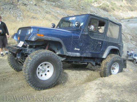 1987 Suzuki Samurai - A modified Jeep Wrangler YJ navigates an off-road trail, with another Jeep in the background.