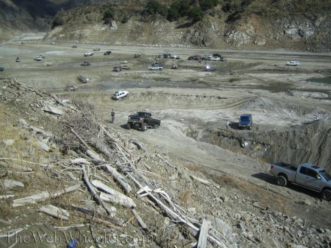 1987 Suzuki Samurai - Multiple off-road vehicles are gathered in a dusty, rocky terrain, with some navigating the landscape.