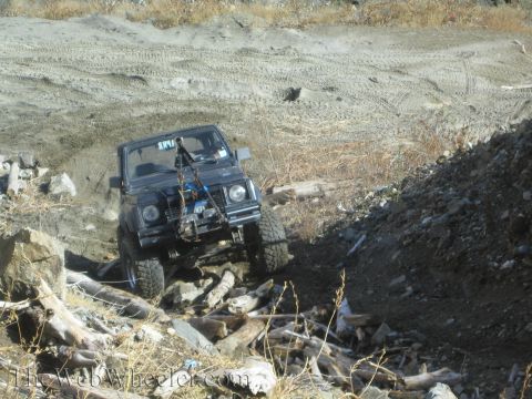 1987 Suzuki Samurai - Suzuki Samurai tackling a challenging off-road course with debris and rough terrain.