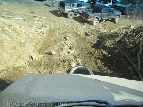 1987 Suzuki Samurai - Several off-road vehicles navigate a challenging dirt track with rocky terrain.