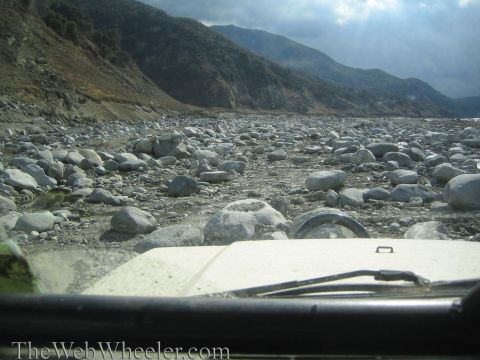 1987 Suzuki Samurai - A white Jeep Wrangler navigates a rocky, mountainous landscape.
