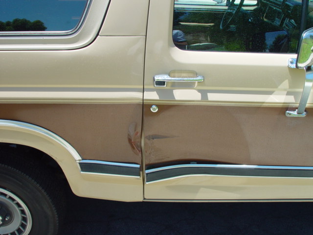 Side of tan and brown Bronco showing dented, scraped lower driver door panel
