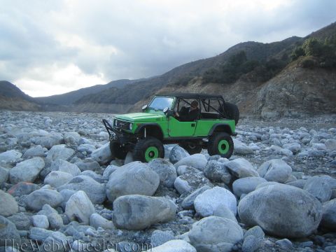 1987 Suzuki Samurai - Modified 1987 Suzuki Samurai navigating a rocky riverbed under a cloudy sky.
