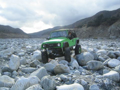 1987 Suzuki Samurai - A modified 1987 Suzuki Samurai drives through a rocky terrain under a cloudy sky.