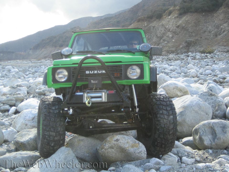Green 1987 Suzuki Samurai front view with winch on rocky terrain