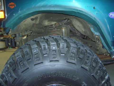 1996 Ford Bronco - Close-up of a teal Ford Bronco's wheel well, showing a Mickey Thompson tire and a Harley-Davidson emblem on the fender.