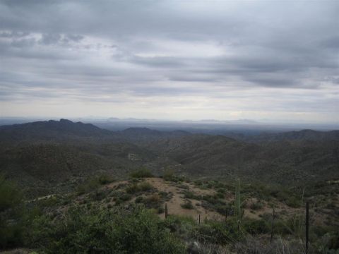 1987 Suzuki Samurai - Overcast sky above a vast desert mountain range with sparse vegetation and cacti.