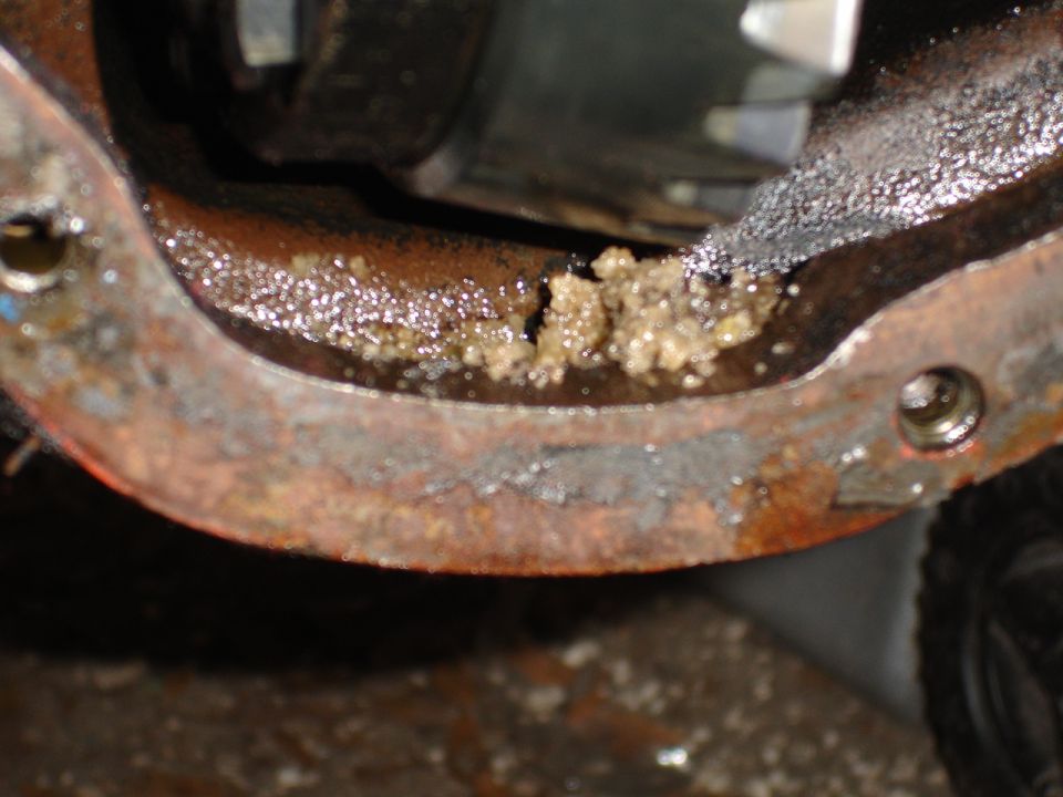 Differential housing showing rust and a buildup of light brown sludge