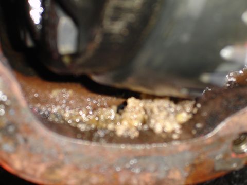 1989 Ford Bronco - A close-up view shows a strange, granular substance within a rusty metal component, possibly a differential housing.