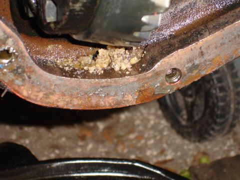 1989 Ford Bronco - Close-up of a rusty differential housing containing a strange, granular substance, with a tire visible in the background.