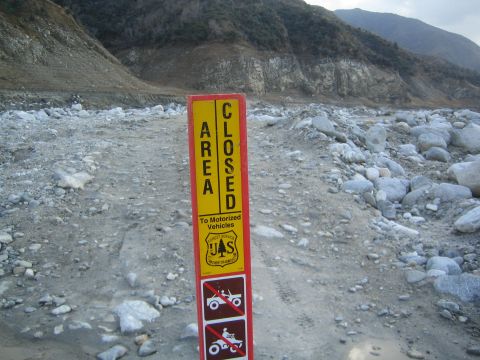 1987 Suzuki Samurai - A sign indicates an area is closed to motorized vehicles, set against a rocky, mountainous backdrop.