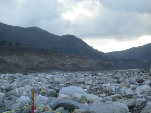 1987 Suzuki Samurai - A wide shot of a rocky riverbed with mountains in the distance under a cloudy sky.
