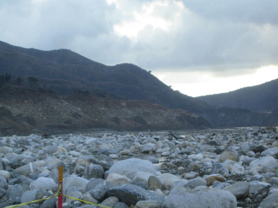 Rocky riverbed with mountains under cloudy sky