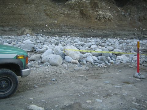 1987 Suzuki Samurai - A green truck is parked on a rocky surface near a cliff face.